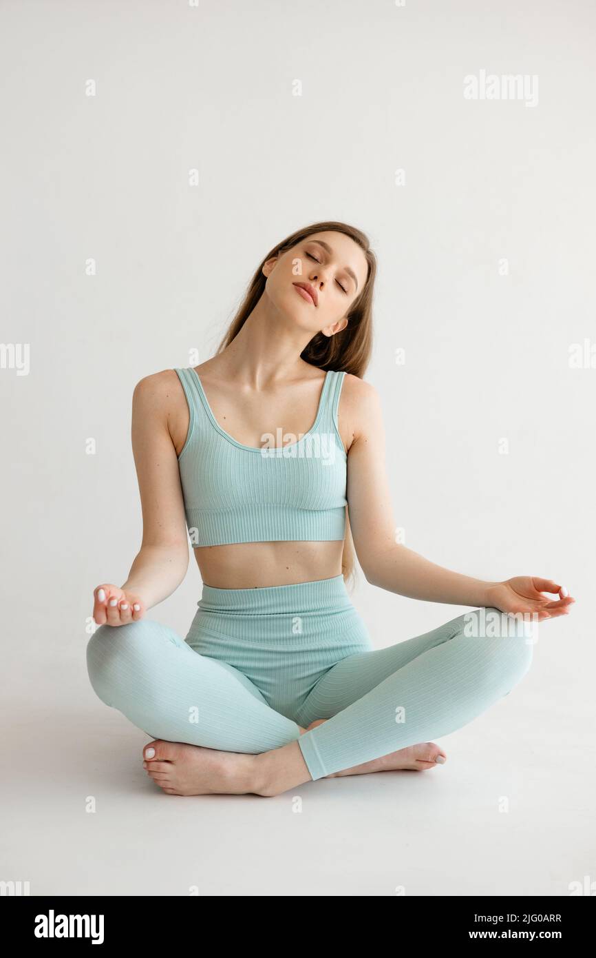 Beautiful athletic girl sitting in a lotus position on a white ...