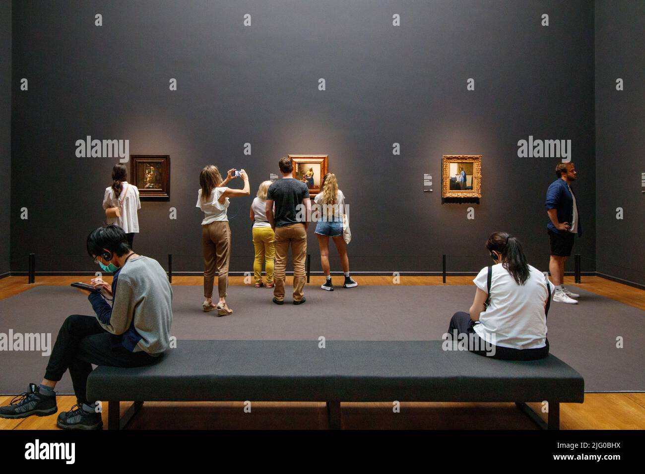 People looking at the Vermeer picture The Milk Maid, one of his most famous paintings on show in the Rijksmuseum, Amsterdam. Stock Photo