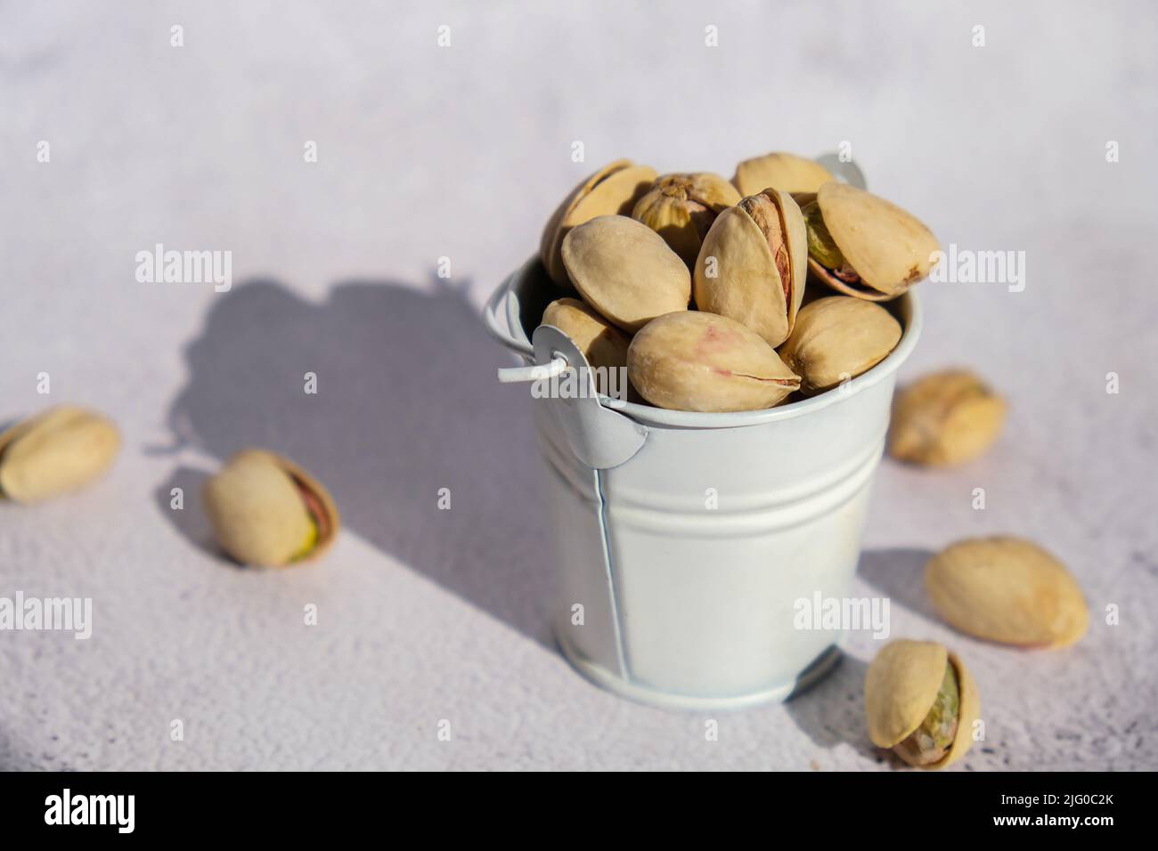 Pistachios in white bucket on concrete background. Healthy and dietary nutrition. Concept of