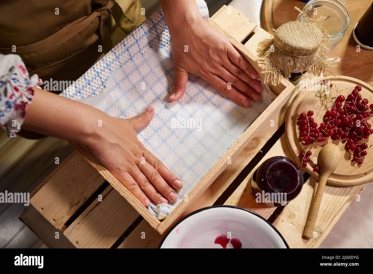 Details Hands of a woman housewife arranging jars with handmade jam upside down in a wooden
