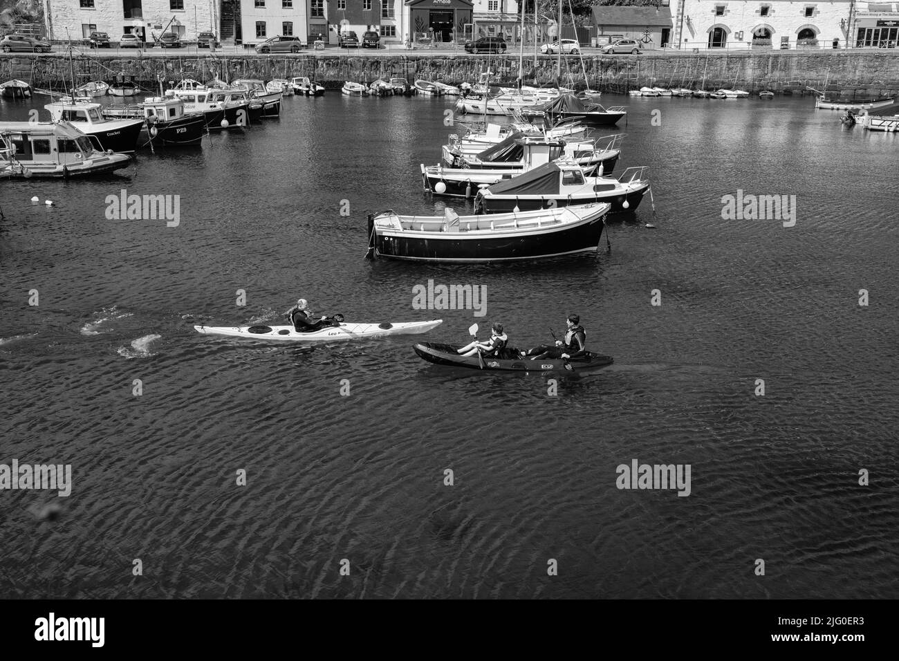 Tourists enjoying kayaking in the inner harbour at Porthleven, Cornwall Stock Photo