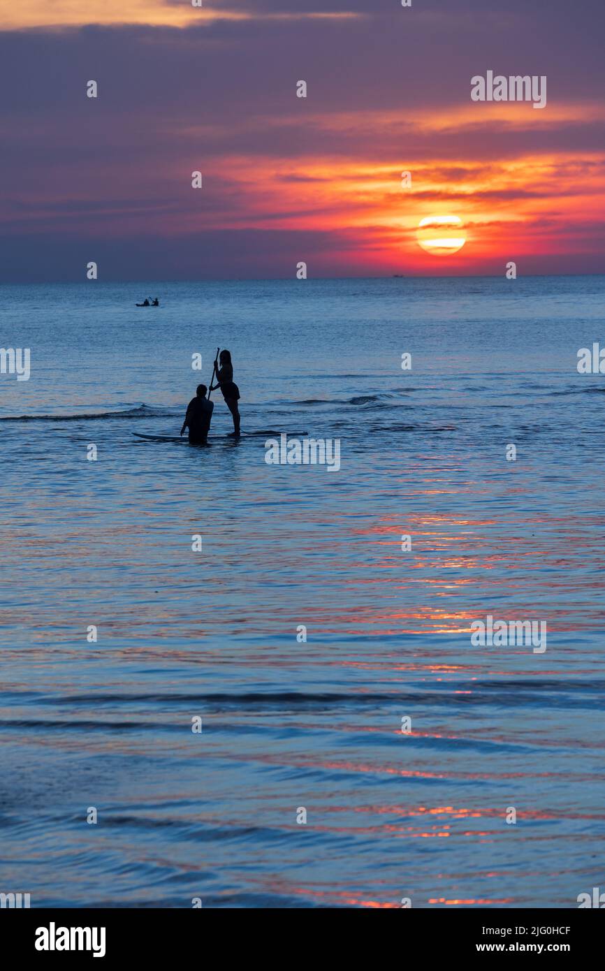 Two people silhouette over a colorful sunset on the sea Stock Photo