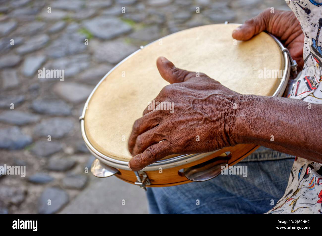 Hands and instrument of percussionist playing tambourine in the streets of the famous Pelourinho neighborhood in the city of Salvador in Bahia Stock Photo