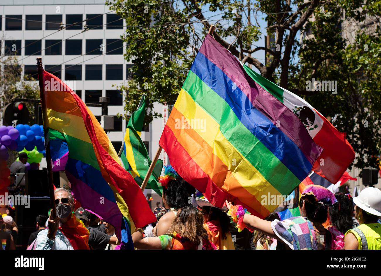 People participating in the pride parade in city with huge rainbow