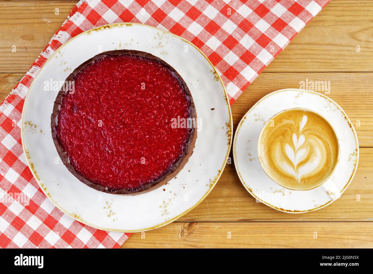 Homemade raspberry and strawberry cheesecake and cup of coffee cappuccino on wooden table. Top view. Stock Photo