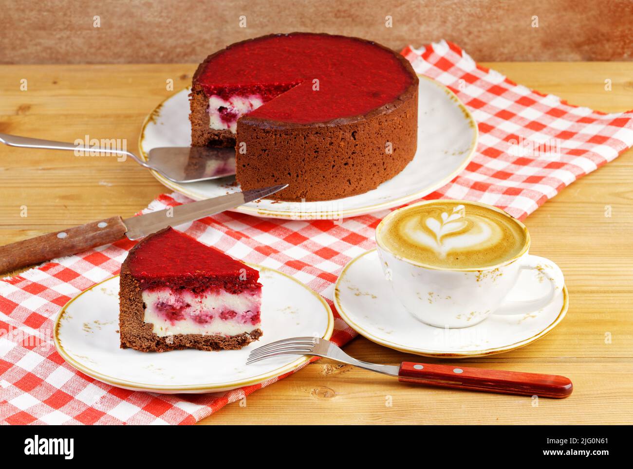 Homemade raspberry and strawberry cheesecake and cup of coffee cappuccino on wooden table. Stock Photo