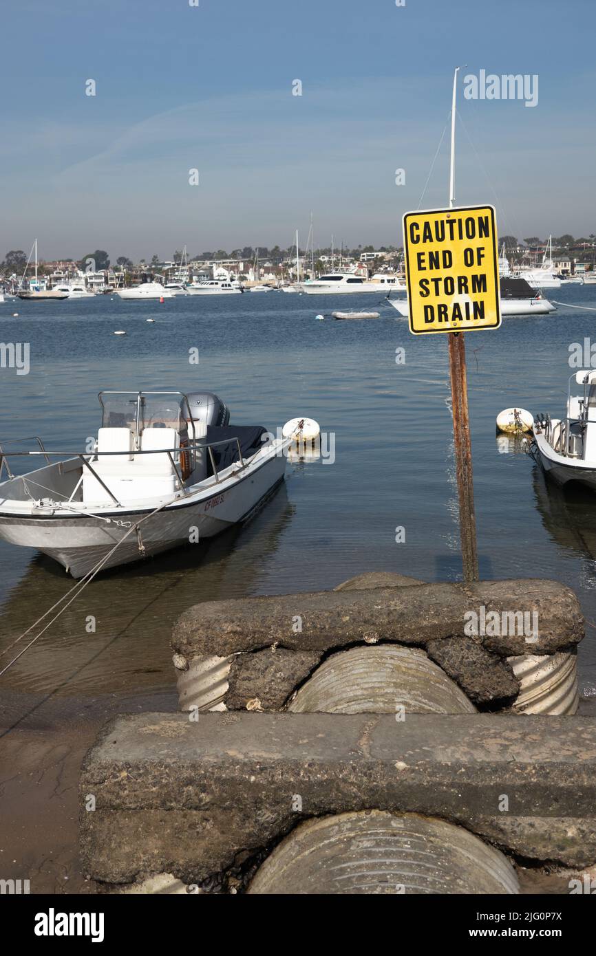 Storm Drain and caution sign in Newport harbor California USA Stock Photo