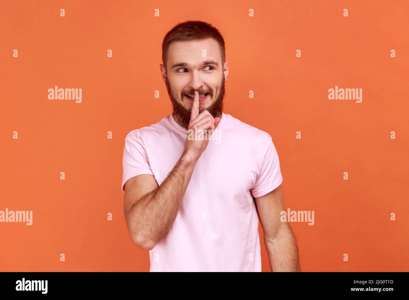 Portrait of positive bearded man showing hush with finger on his lips ...