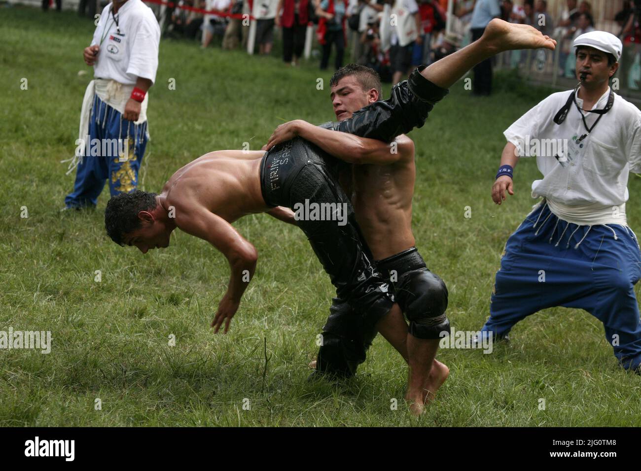 Kırkpınar (Turkish Oil Wrestling). Wrestlers fight during the 648th Kırkpınar Tournament in Edirne, Turkey, on 4 July 2009. Kırkpınar wrestlers compete stripped to the waist and smeared their bodies with olive oil. Wrestlers wear only black leather trousers called kisbet. The name of the wrestler is embossed by metal rivets behind. The oiled body is extremely slippery, and the only reliable way to capture an opponent is push an arm through the kisbet and grab the other end of the leg. Stock Photo