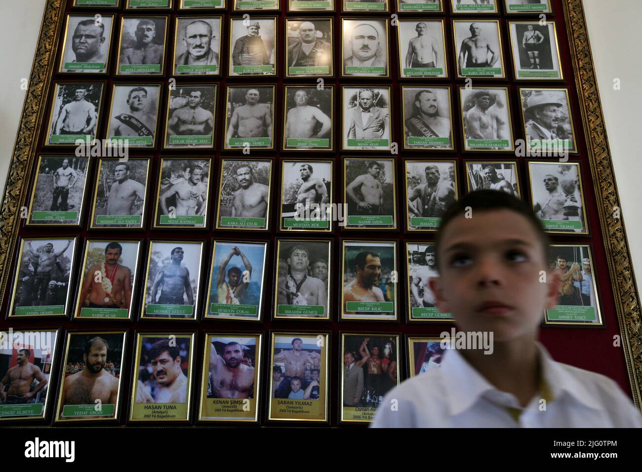 Kırkpınar (Turkish Oil Wrestling). Young boy pictured in front of the stand with photographs of the champions of the Kirkpinar Tournament won the competition in different years of the 20th century in the Kırkpınar House (Kırkpınar Museum) in Edirne, Turkey. Stock Photo