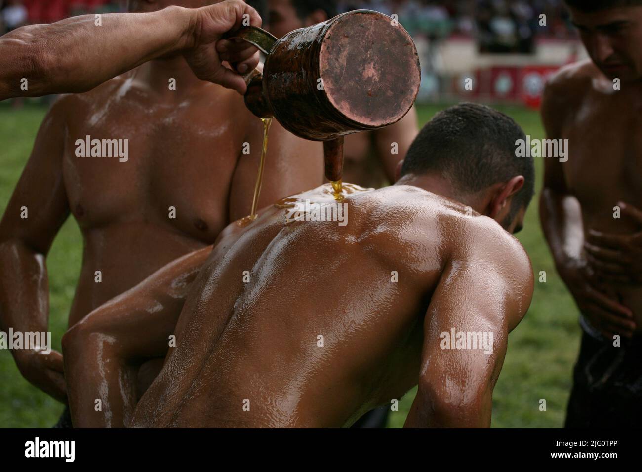 Kırkpınar (Turkish Oil Wrestling). Tournament staff member pours olive oil on the wrestler to prepare him for fighting during the 648th Kırkpınar Tournament in Edirne, Turkey, on 4 July 2009. Kırkpınar wrestlers compete stripped to the waist and smeared their bodies with olive oil. About three tons of olive oil is used each year during the Kırkpınar Tournament. Stock Photo