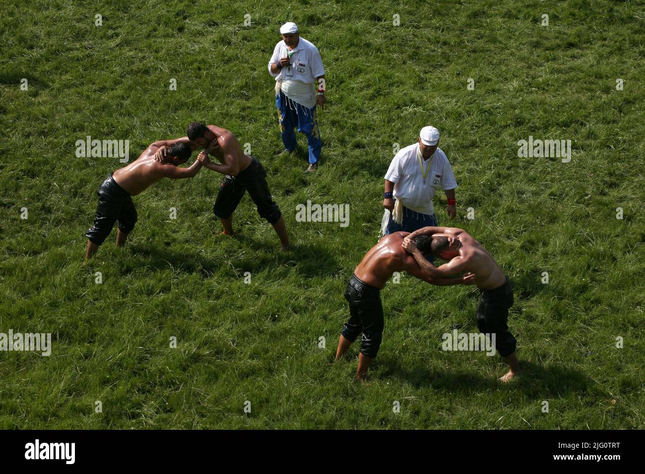 Kırkpınar (Turkish Oil Wrestling). Referees keep a close eye as wrestlers fight during the 648th Kırkpınar Tournament in Edirne, Turkey, on 4 July 2009. Kırkpınar wrestlers compete stripped to the waist and smeared their bodies with olive oil. Wrestlers dressed only black leather trousers called kisbet. The name of the wrestler is embossed by metal rivets behind. Stock Photo