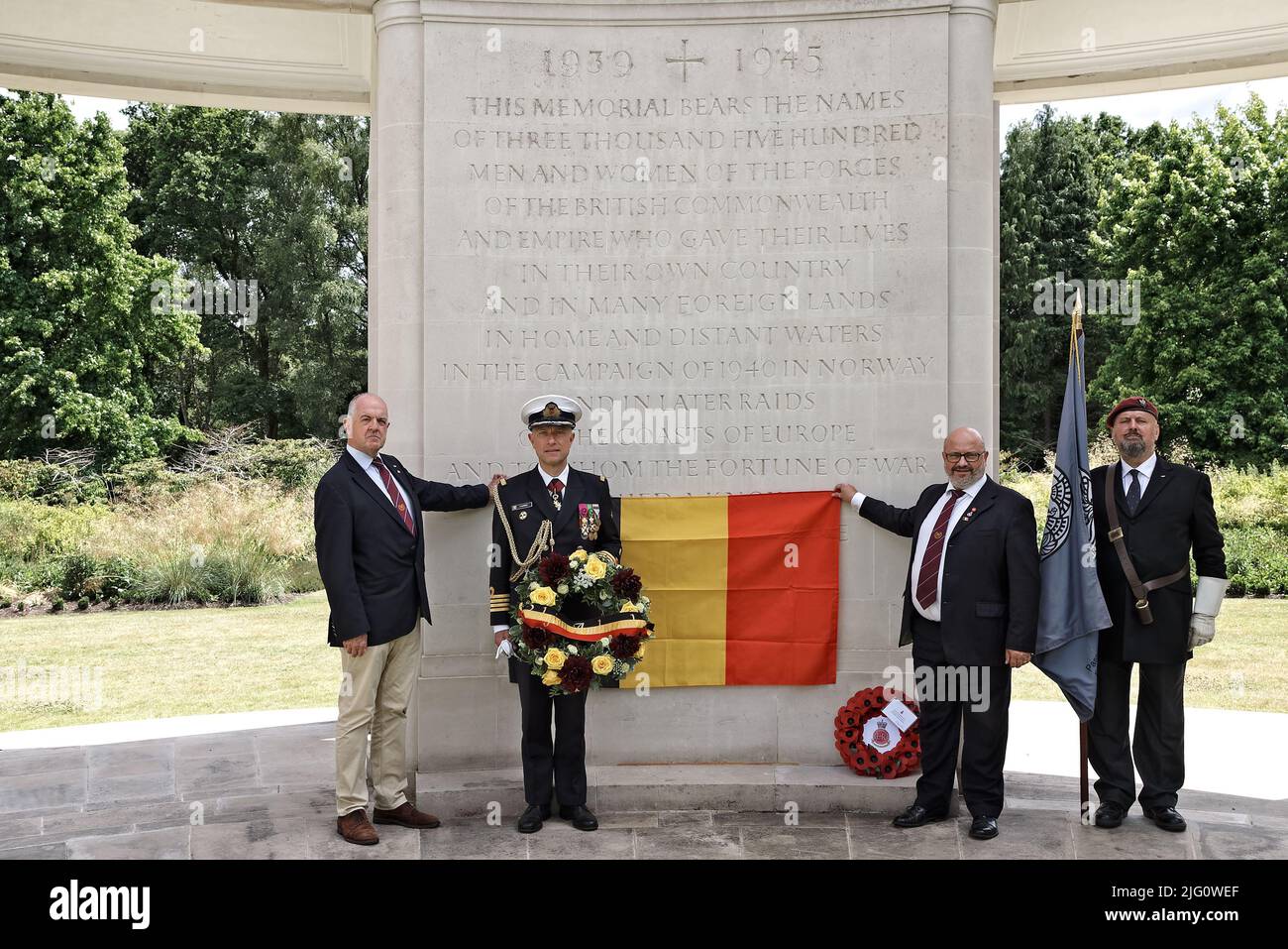 Sun 3rd July 22. At the 1939-45 Brookwood Memorial holding a service for Belgian SOE Agents without a grave are L to R: Paul McCue, author & military historian; Captain (Naval) Renaud Flamant Defence Attaché of the   Embassy of the Belgian Kingdom in the UK holding his Ambassadors wreath; Kevin Davis, Chair of the Brookwood Last Post Association and Edward Jones, Artist Rifles Standard Bearer . The Belgian National flag is shown & a wreath previously placed by the RMAS. Stock Photo