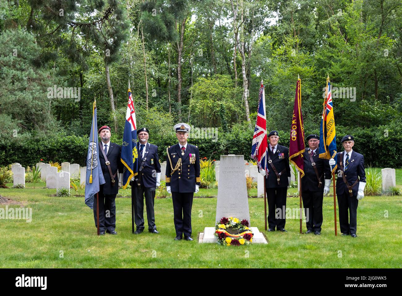 Sun 3rd July 22.Captain (Naval) Flamant, Belgian Defence Attaché having placed the Belgian Ambassador's wreath at the WW2 Memorial stands with Standard Bearers to honour the Belgian fallen interred in graves shown in the background. Extreme left - Edward Jones of  the educational charity The Trench Experience bears the Artists Rifles Standard. Stock Photo