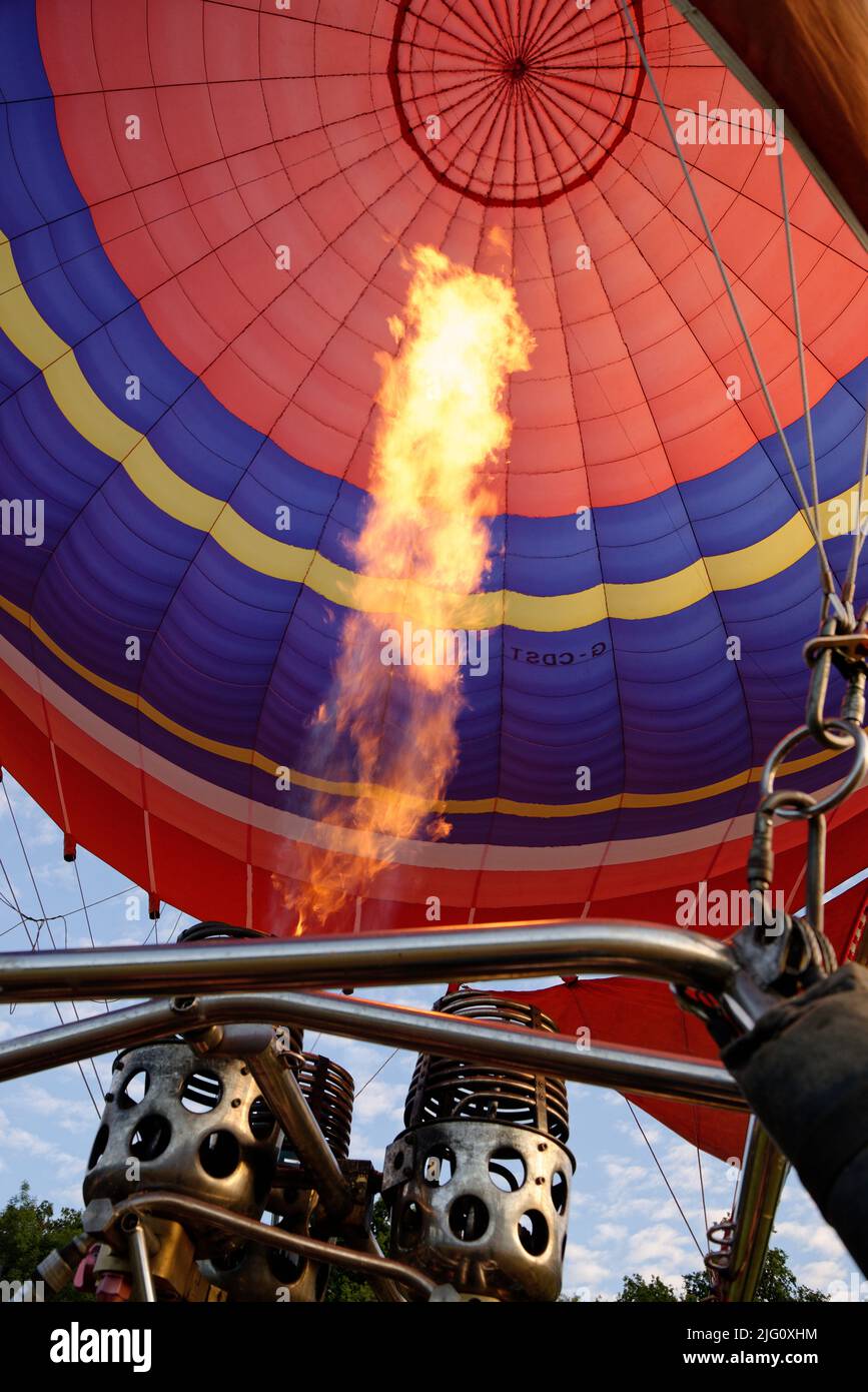 A hot air balloon. Orange flames fire into the balloon envelope to fill it with hot air. Stock Photo
