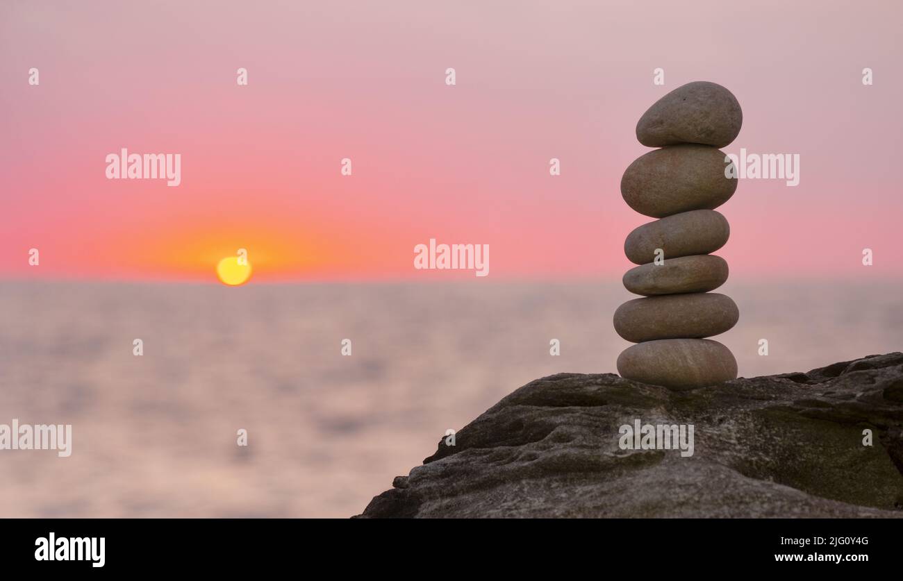 Stacked stone tower on the beach by the sea with the sunset out of ...