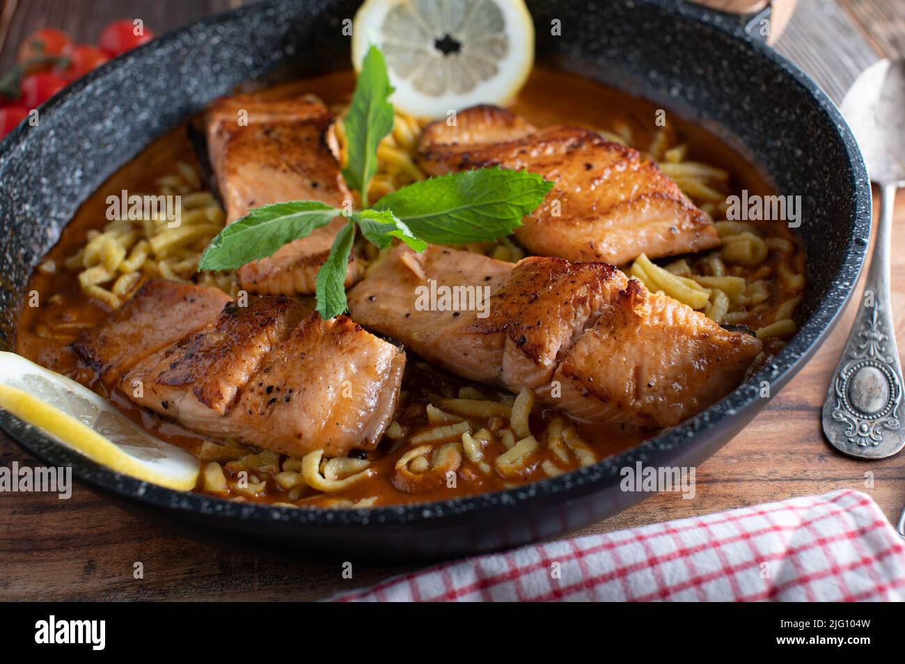Pan seared salmon fillet with tomato cream sauce and spaetzle noodles Stock Photo
