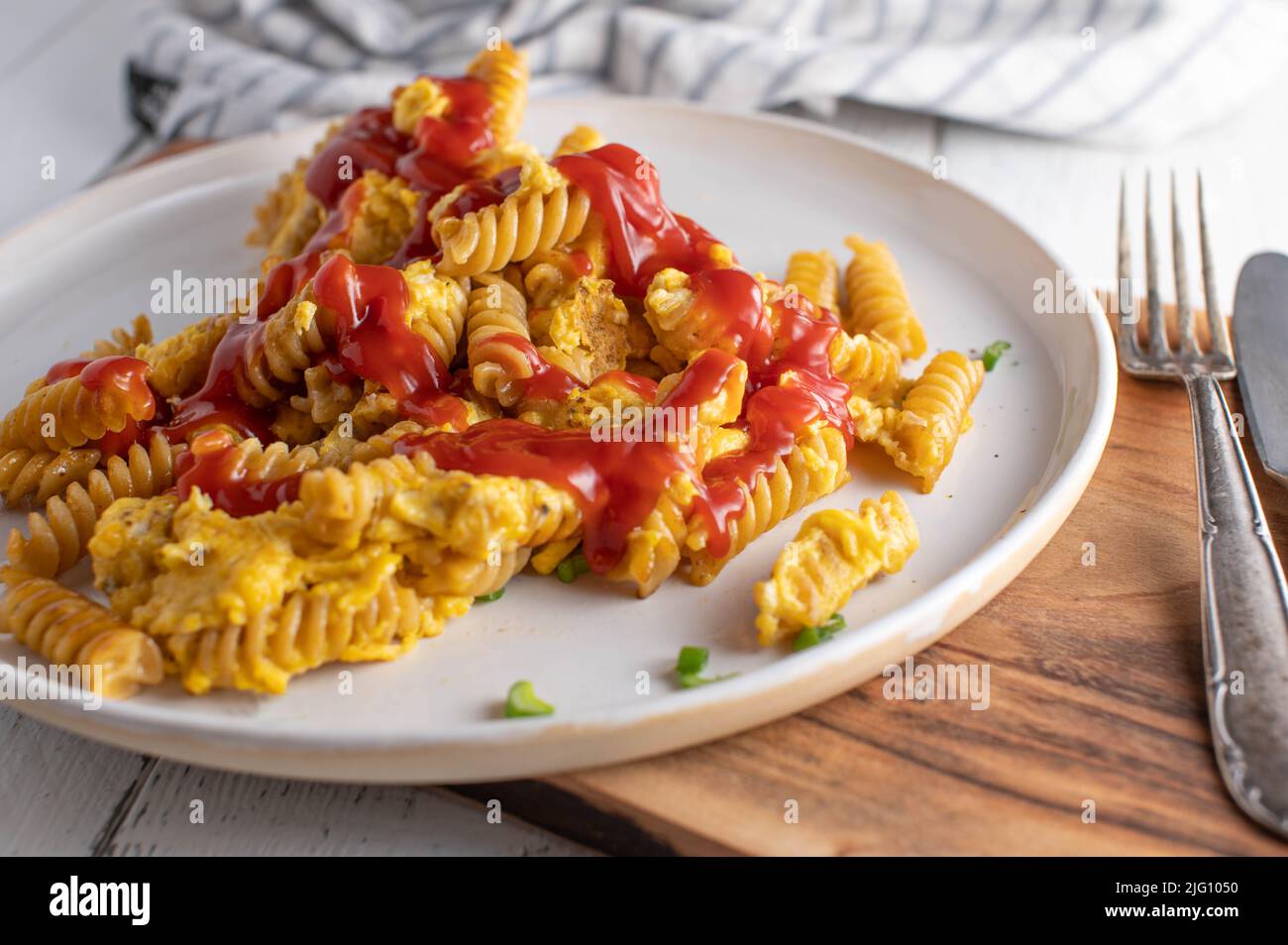 Pasta with fried eggs and ketchup. Homemade fast food. Unhealthy eating Stock Photo