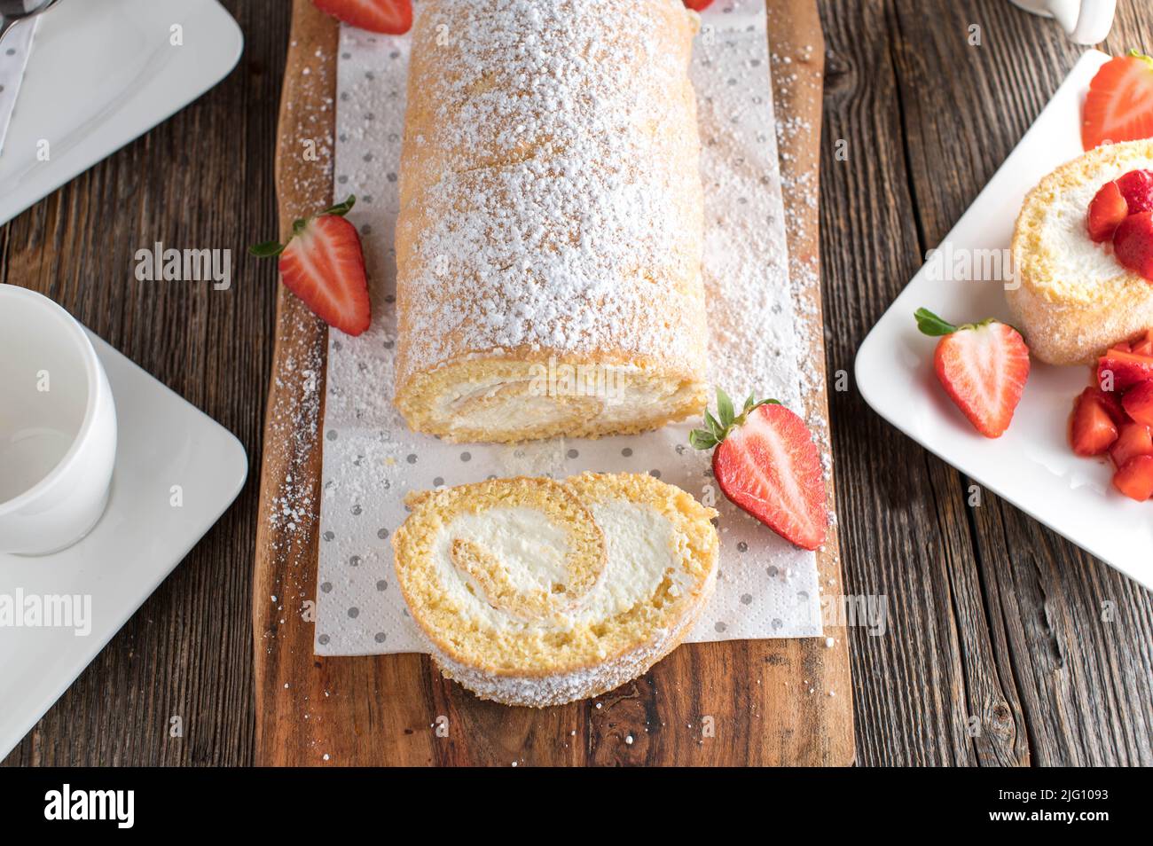 Swiss roll with cream filling  isolated on wooden table Stock Photo