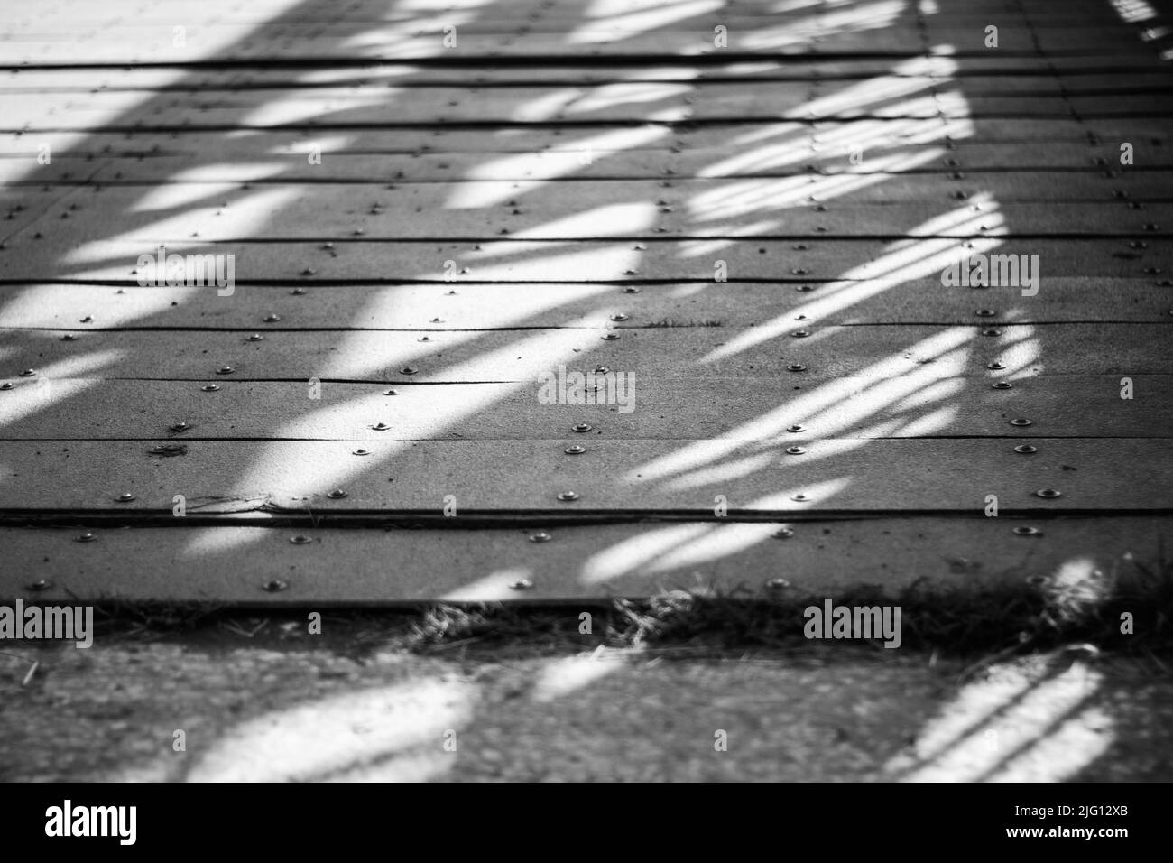 A black and white close up of shadows and light on a footbridge. Stock Photo