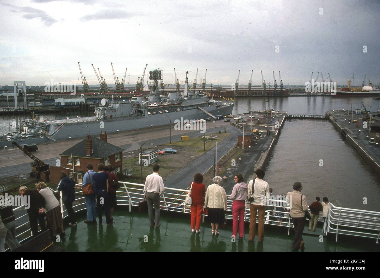 1981, historical, people standing looking over King George Dock, Hull, England, UK, with a Royal Navy ship moored. The port was opened by King George V on June 1914. Stock Photo