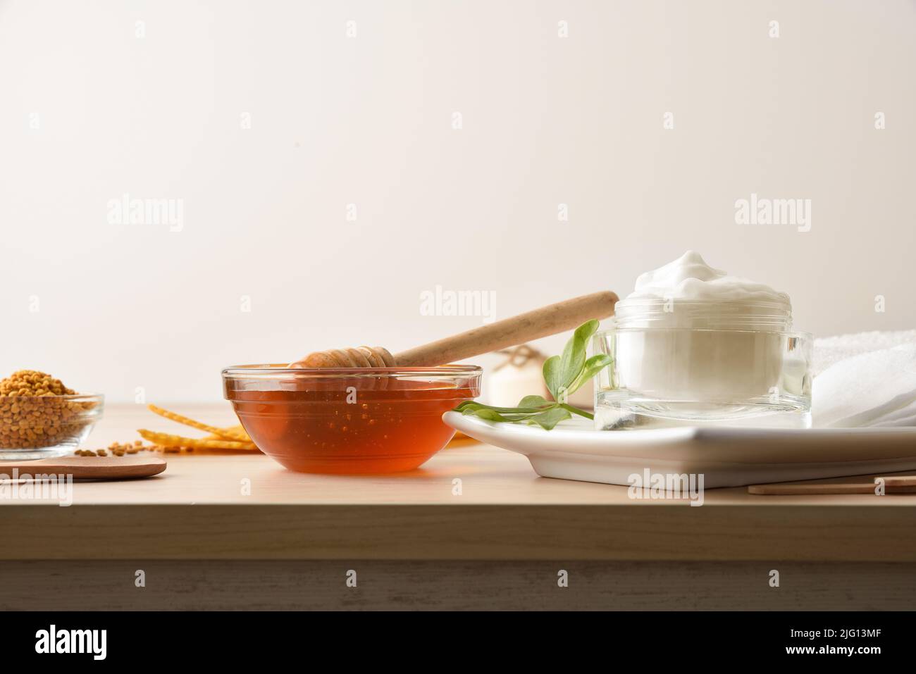 Cream with honey extracts and container with honey on wooden table and white isolated background. Horizontal composition. Front view. Stock Photo