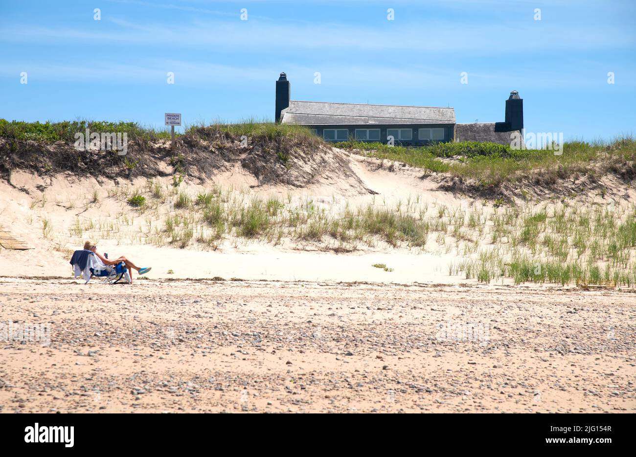 On the beach sunning in front of summer home.  Dennis, MA (Cape Cod) USA Stock Photo