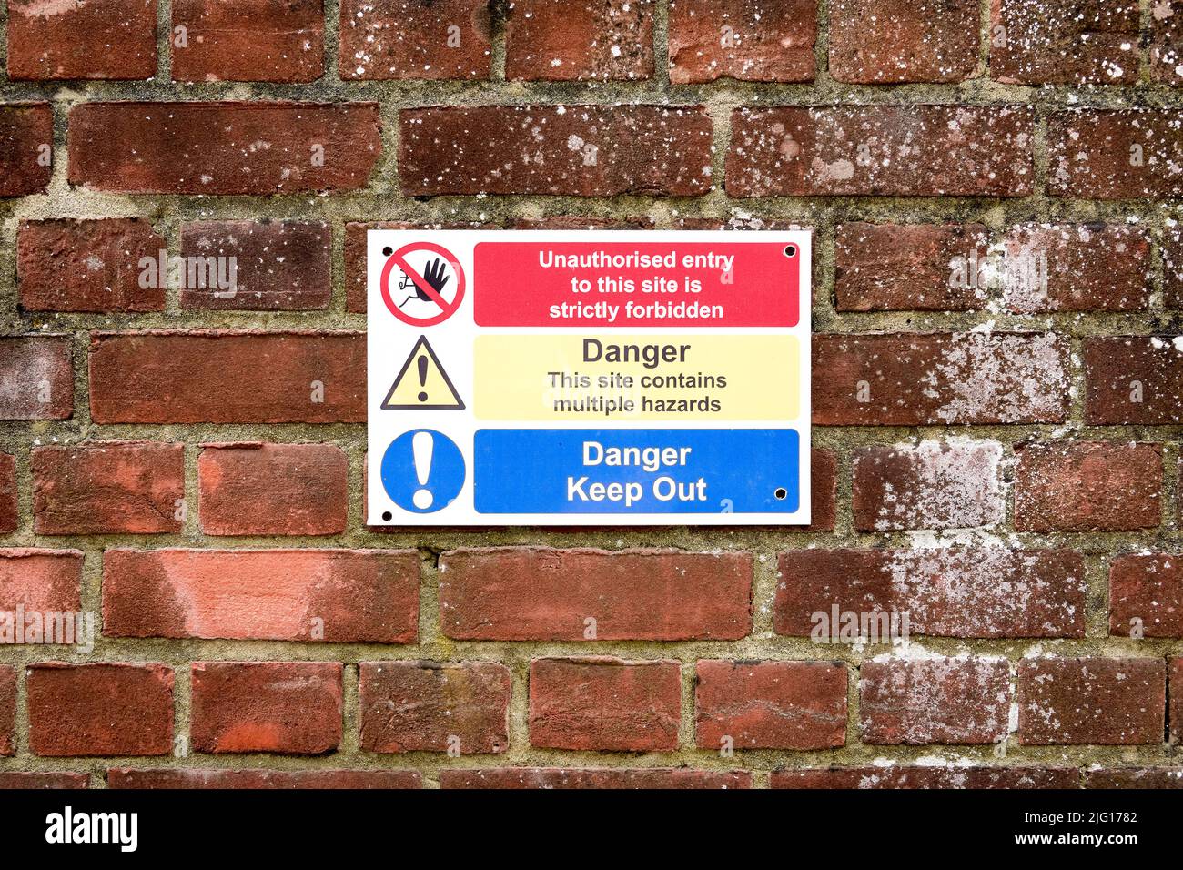 Danger keep out and hazard warning sign on red brick wall Stock Photo