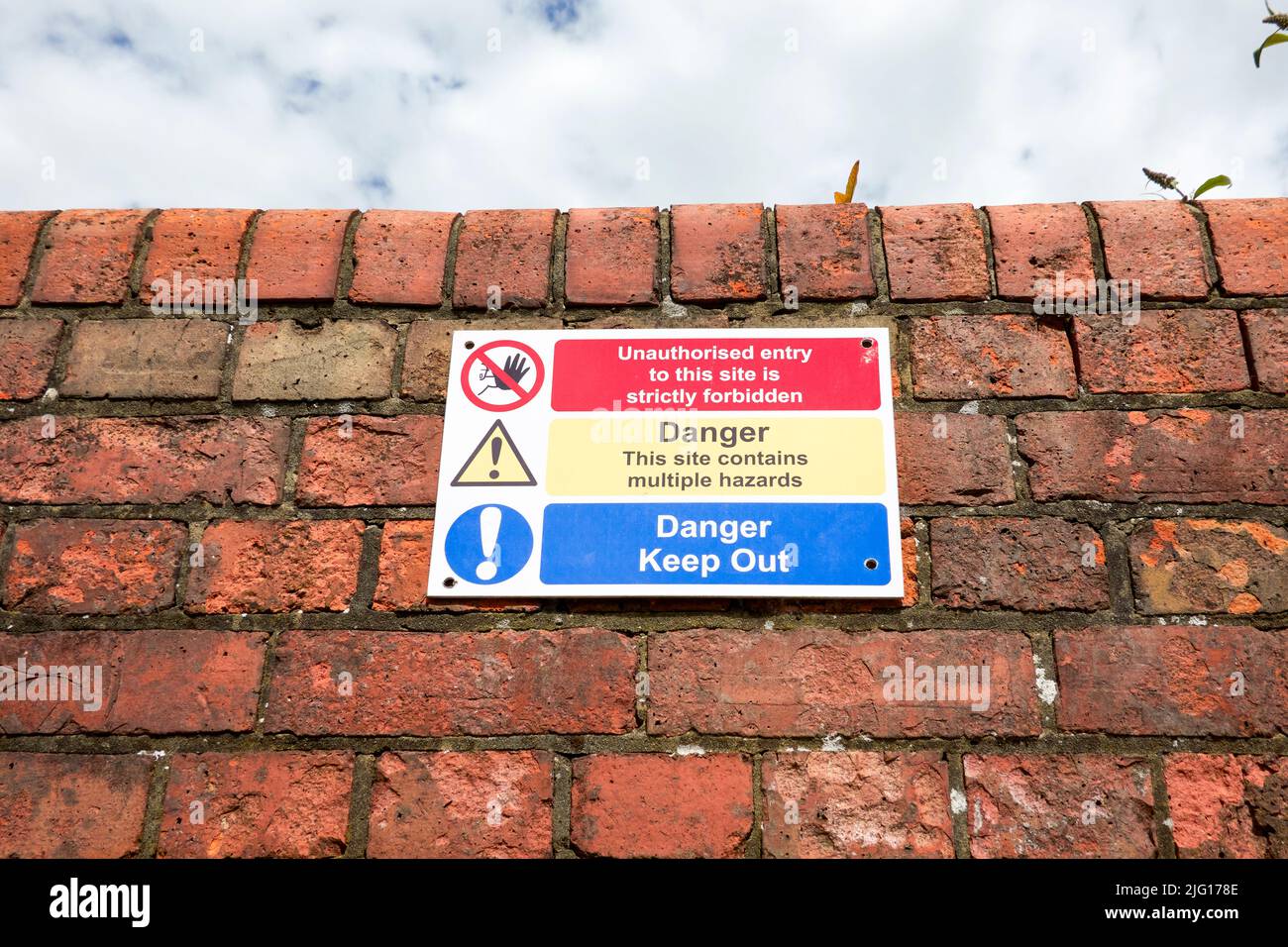 Danger keep out and hazard warning sign on red brick wall Stock Photo