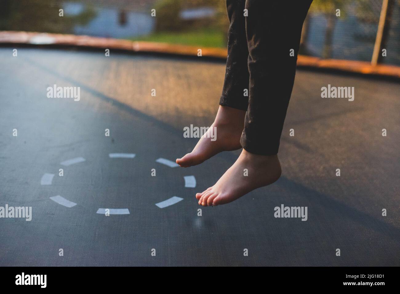 A seven year old girl child jumping on a trampoline. Stock Photo