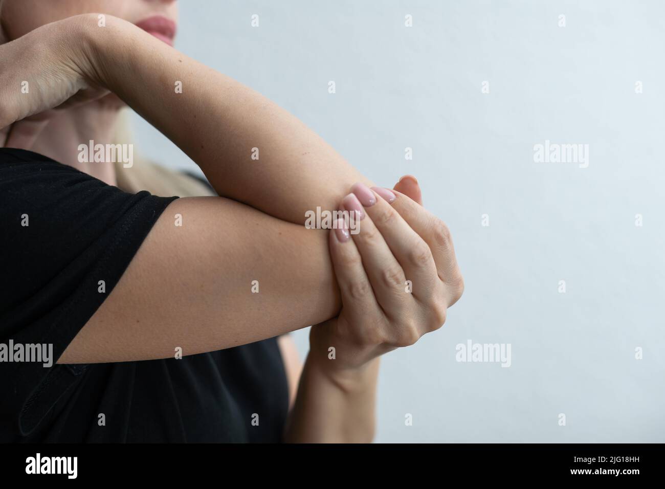 women elbow pain, holding hand to spot of elbow pain. Arm pain and