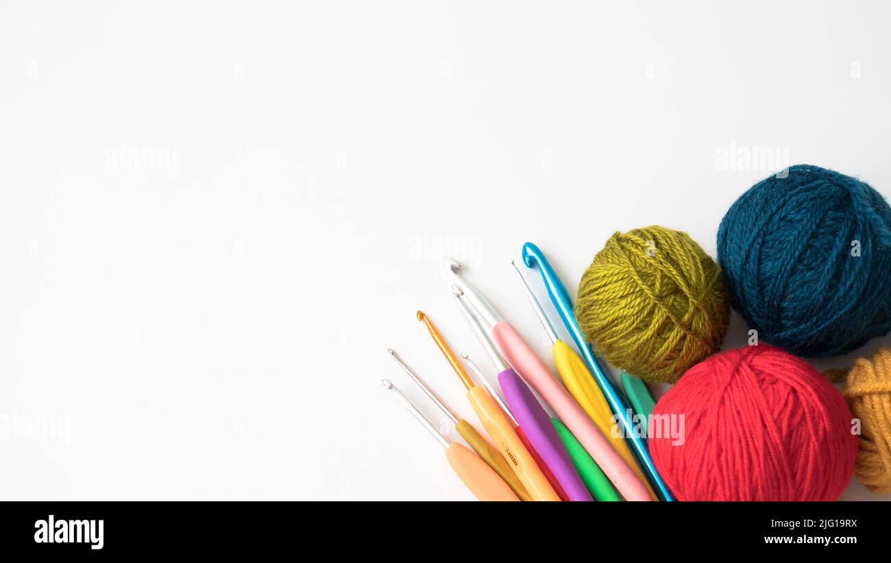 Colorful balls of wool with crochet hooks. Copy space, space for text on the left side. Top view, above, up. Flat lay photo. Stock Photo