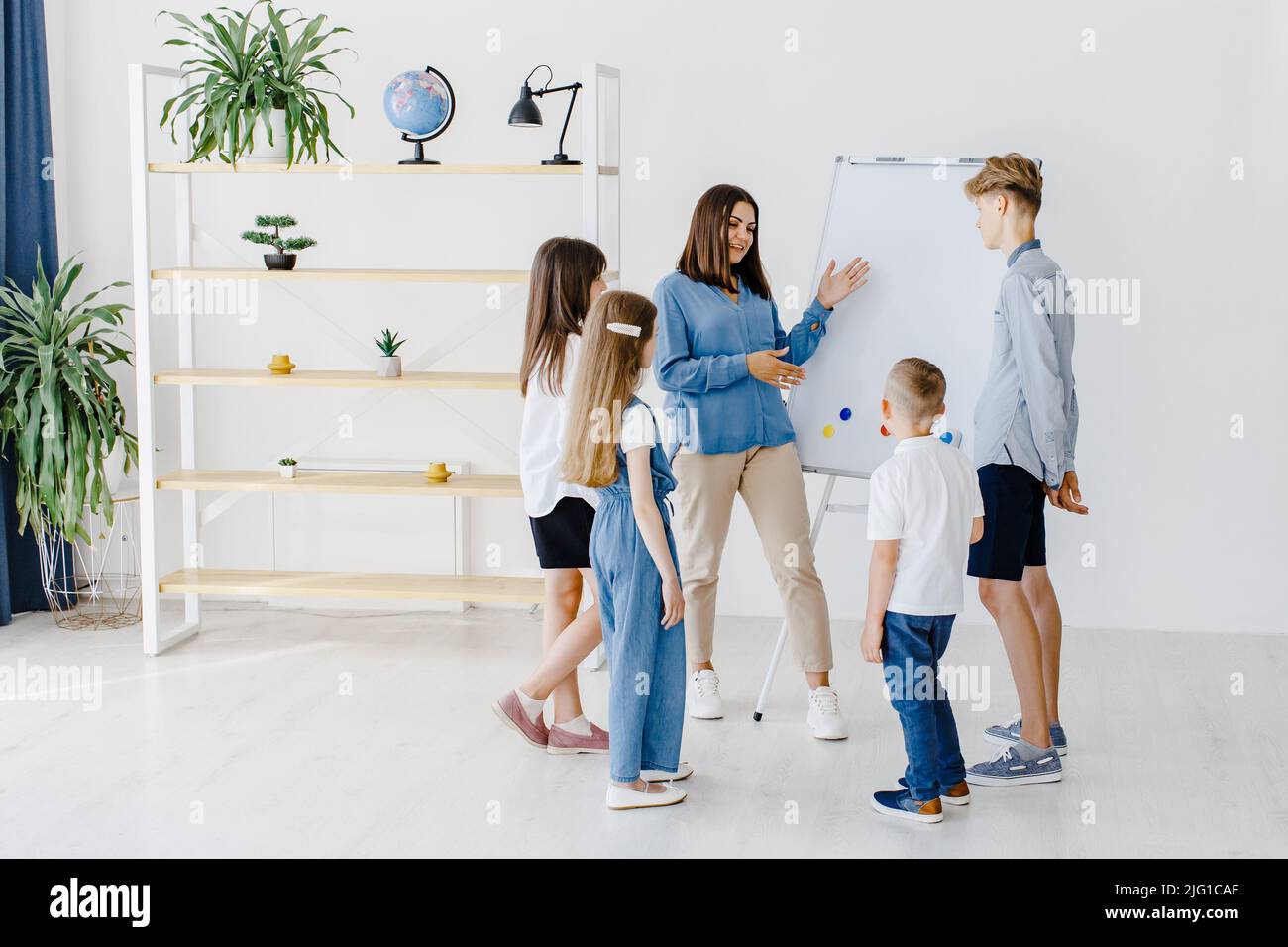 Explaining lesson and using board. Group of children students of different ages in class at school with teacher. Stock Photo