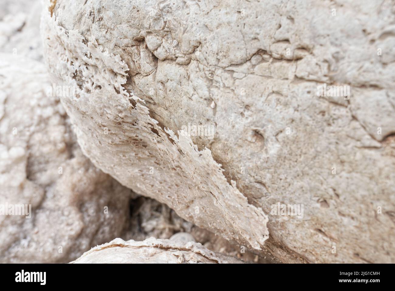 Sand and stones covered with crystalline salt crust on shore of Dead Sea, closeup detail Stock Photo