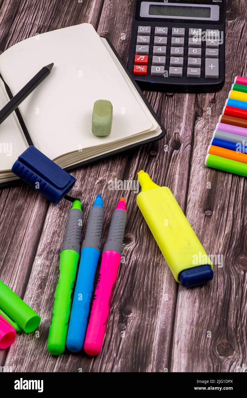 Various school supplies such as markers, colored pens and markers, notebook and eraser. On top of a wooden table. Back to school. Stock Photo