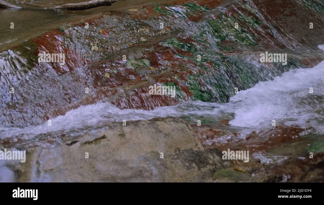 Light water close-up.Creative.A small waterfall that flows down the stones with clear water and slightly bubbling. High quality 4k footage Stock Photo
