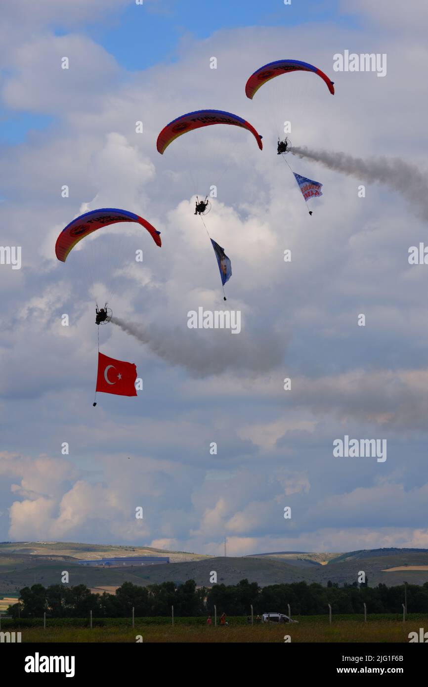 Three Parachutists at cloudy sky towing flag, banner and Poster of Ataturk for an airshow in Turkey Stock Photo