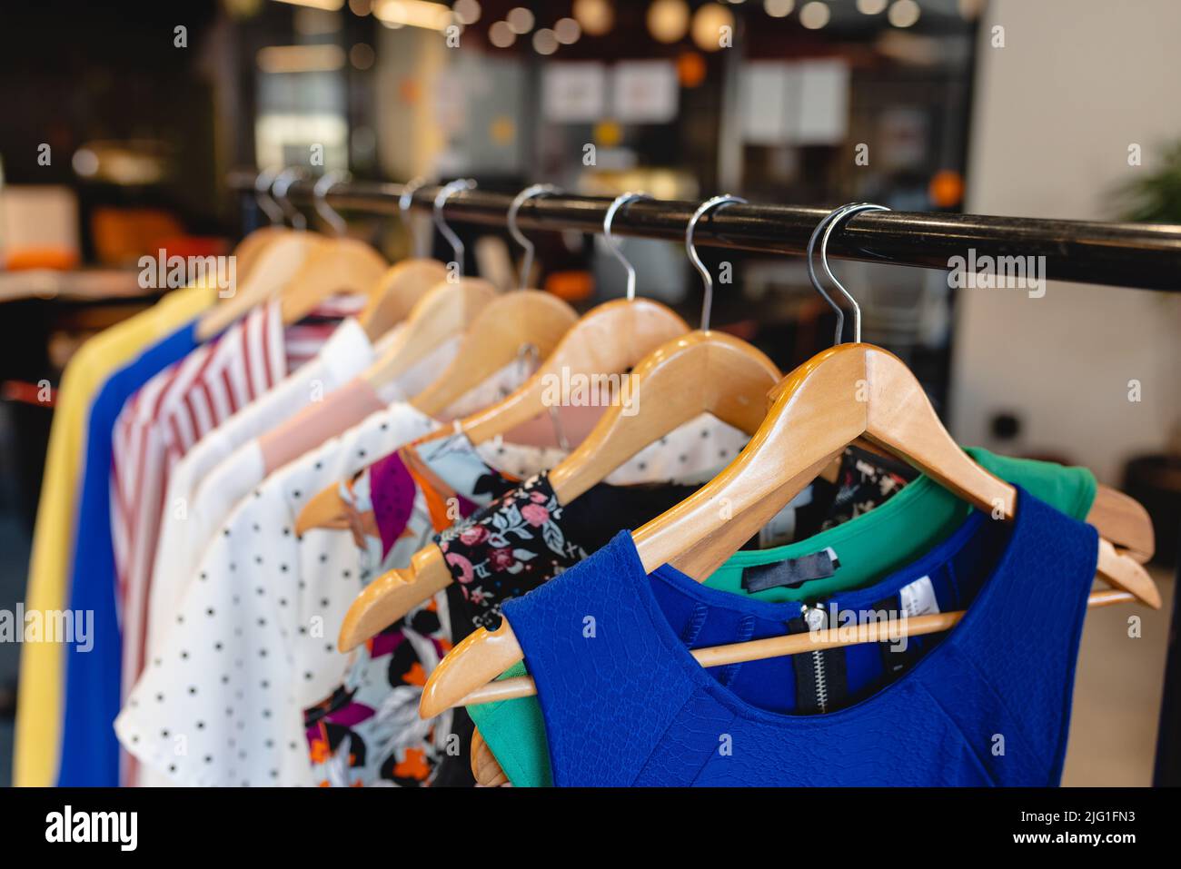 Various garments hanging on coathangers in fashion studio Stock Photo