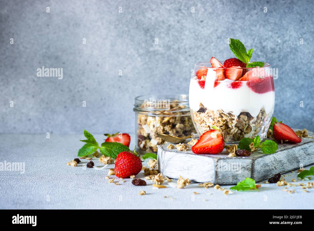 Parfait with cream or yogurt, jam and fresh strawberries in the glass