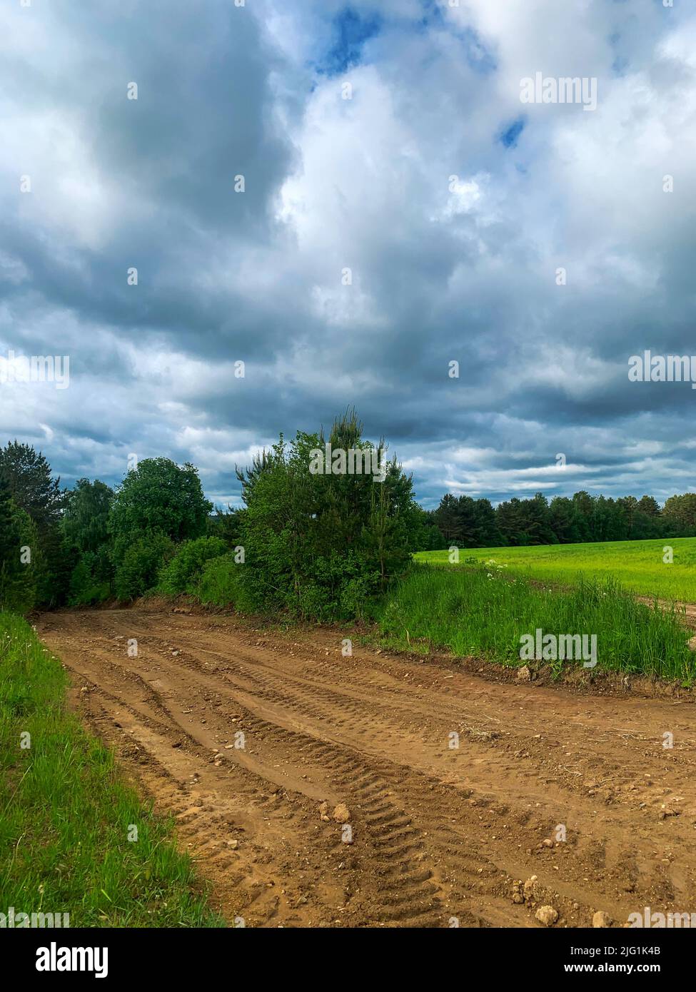 Country road by fields. Stormy deep blue sky and white clouds. Natural landscape background Stock Photo