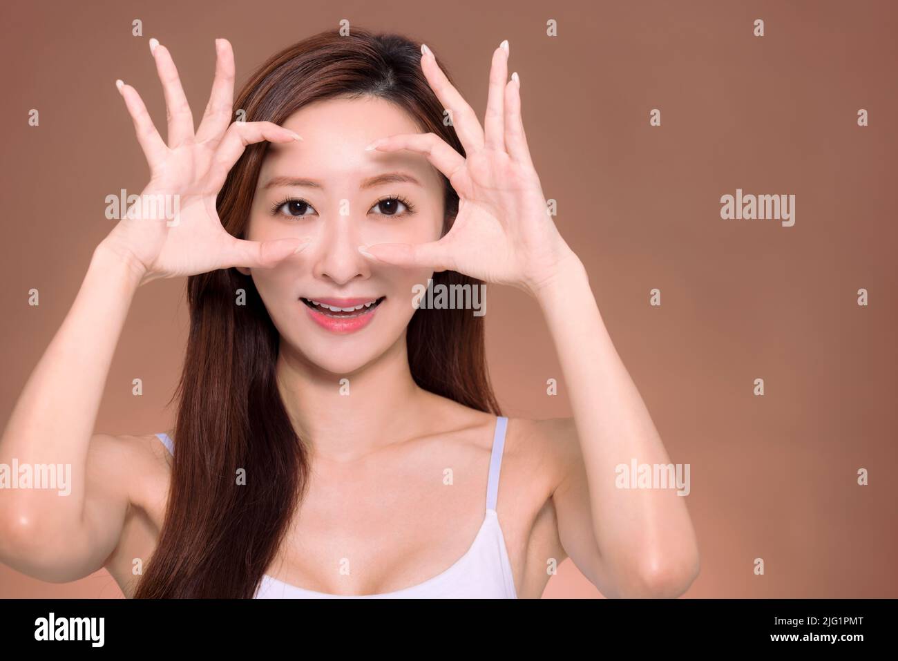 Young beautiful  woman  doing ok gesture with hand smiling, eye looking through fingers with happy face. Stock Photo