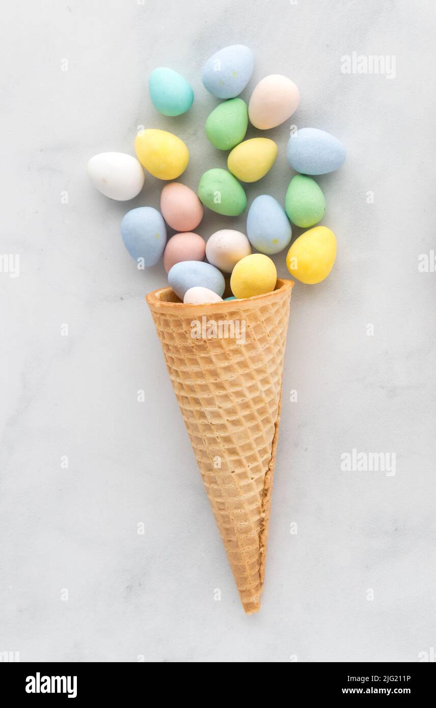 Single waffle cone filled with pastel coloured candy coated chocolates. Stock Photo
