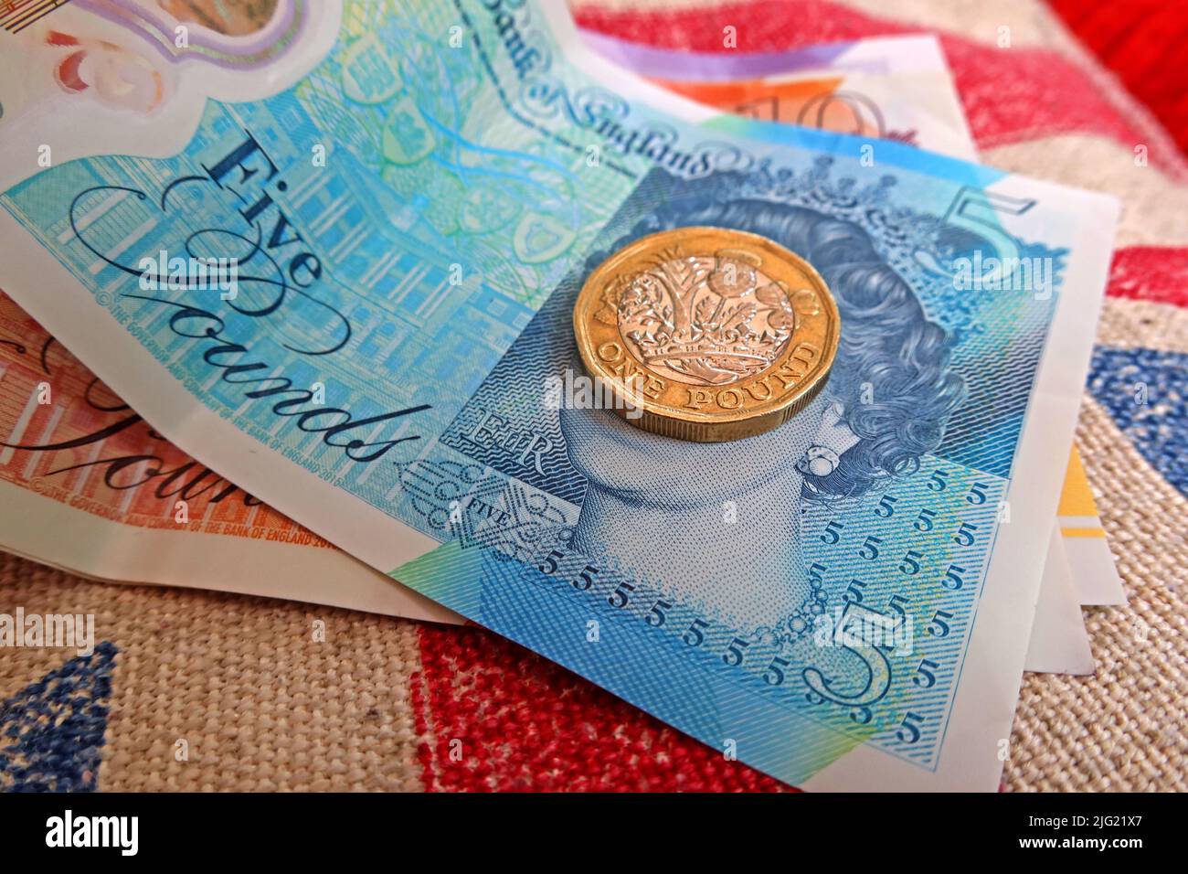Sterling pound notes, bank of England and pound coins on a union jack flag - cost of living crisis, in UK / GB Stock Photo