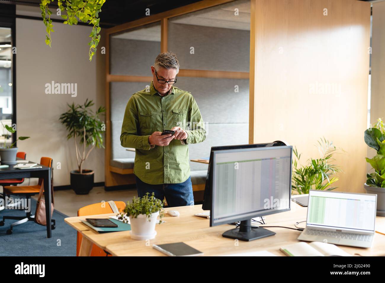 Caucasian mature businessman using smart phone in creative office Stock Photo