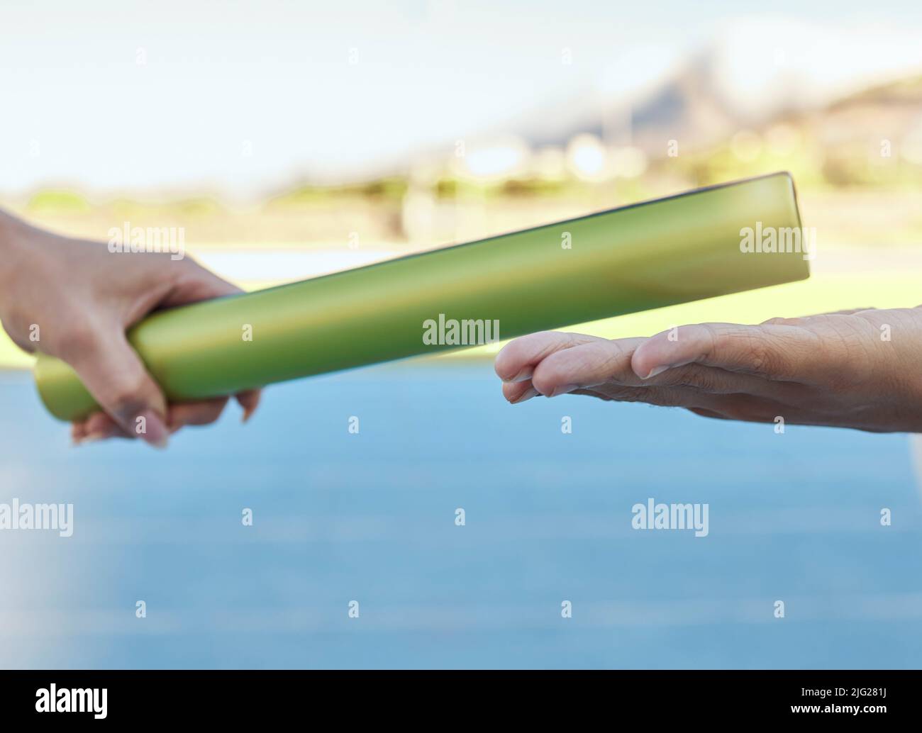 Closeup of two athletes passing a baton during a relay race on a