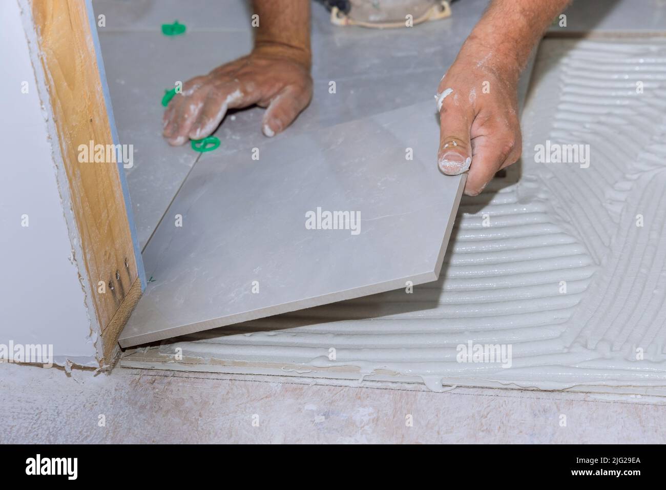Placing ceramic floor tiles on adhesive surface with home construction