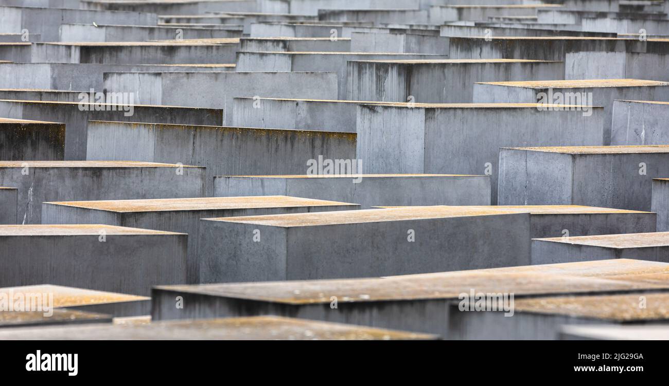 A view of concrete slabs or 'stelae' part of the Memorial to the Murdered Jews of Europe or 'Holocaust Memorial' located south of the Brandenburg Gate. The Memorial to the Murdered Jews of Europe also known as the Holocaust Memorial is a memorial in Berlin to the Jewish victims of the Holocaust, designed by architect Peter Eisenman and Buro Happold. It consists of a 19,000-square-metre site covered with 2,711 concrete slabs or 'stelae', arranged in a grid pattern on a sloping field. They are organized in rows, 54 of them going northñsouth, and 87 heading eastñwest at right angles but set sligh Stock Photo