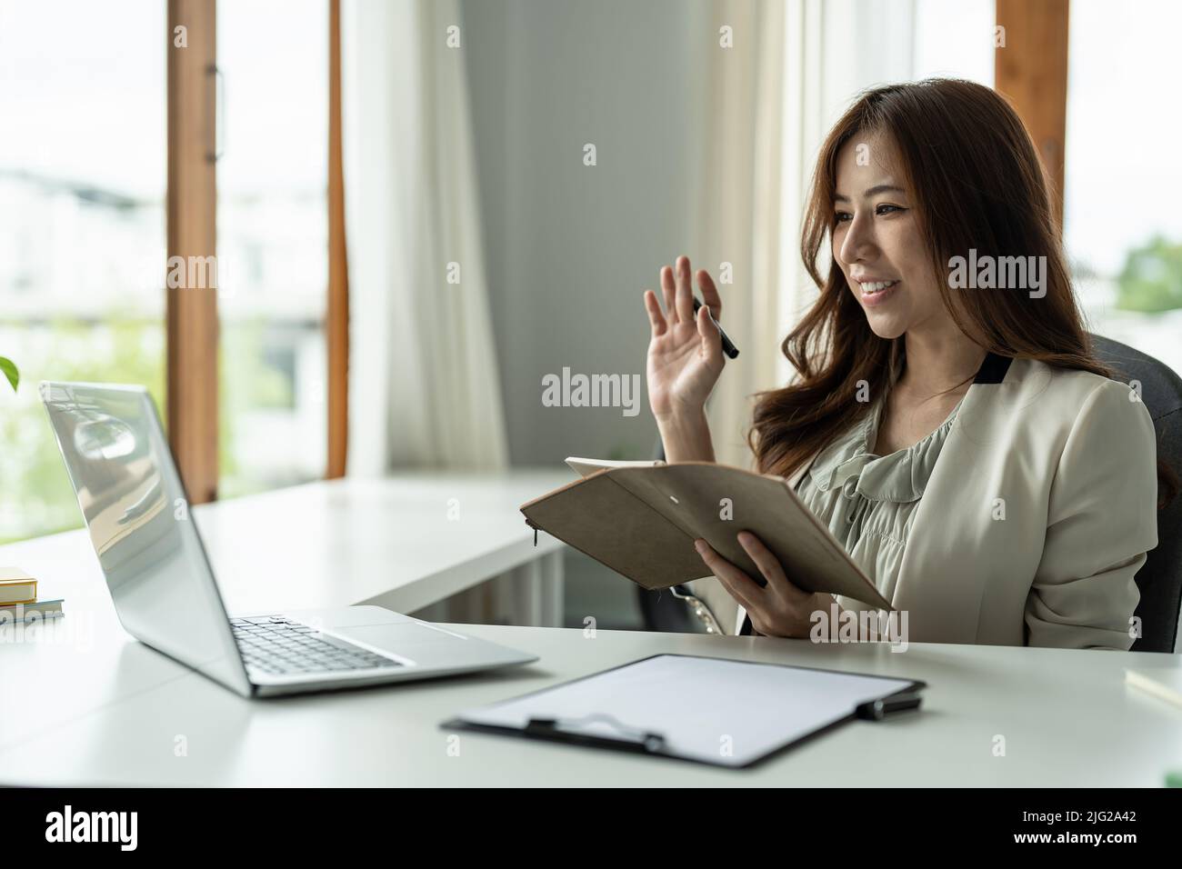 Young asian woman having conference video call using laptop talking to ...