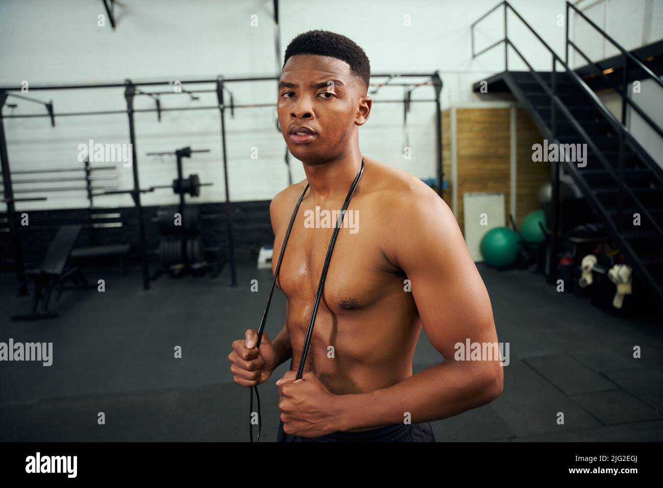 African American male holding skipping rope in the gym. Male athlete looking to the camera during exercise. High quality photo Stock Photo