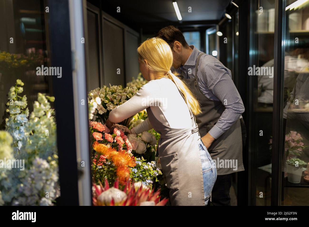 flower shop employees arrange fresh flowers in the fridge Stock Photo